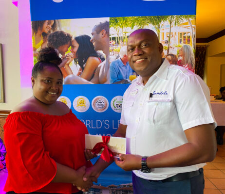 Happy Hearts Early Childhood teacher, Nadine Jarrett-Salabie (left) flashes a winning smile for the camera as General Manager at Beaches Negril, Lancelot Lebert hands her the top prize of a 2 nights/ 3 days stay at any Sandals Resort in Jamaica during the resort’s Teacher’s Day celebration.