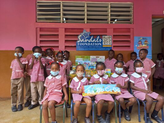 Students of Windsor Basic School showcase a portion of the school supplies donated by the Sandals Foundation. 