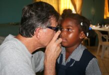 Great Shape! Inc. volunteer conducts an eye exam on a small child during an iCare clinic