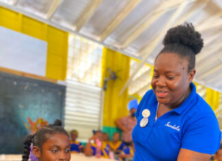 Khari-Grace Andries, student from Negril Primary School being taught on plate placement by Sandals Negril’s Keithia Duncan.
