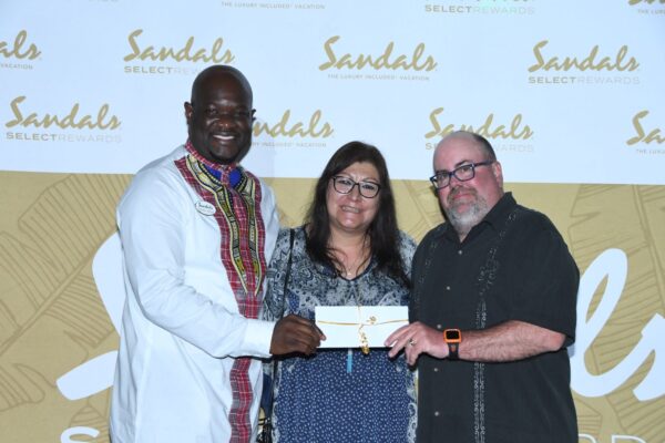 Sandals South Coast General Manager, O’Brian Heron (left) proudly presents returning guests Christian and Elizabeth  Buck,  winners of the grand prize raffle, with a complimentary one week stay at Sandals or Beaches Resorts.