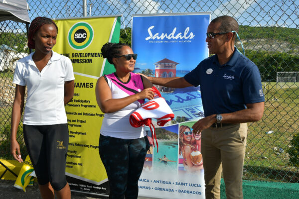 Sandals Montego Bay General manager Christopher Elliott handing over a set of netball bibs as part of his company’s sponsorship of the Flanker SDC Community Netball League to  Tracy-Ann Davis of the organizing committee while Amalya Stewart looks on. Occasion was the Rally to mark the opening of the competition.