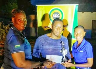 Ashley Simms (right), Sandals regional public relations coordinator for Montego Bay Region, assists Evett Malcolm, Social Development Commission Field Supervisor in handing over The Sandals Trophy to captain Tiray Thoston at the presentation ceremony for the Retirement Community Football League recently.