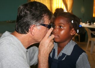 Great Shape! Inc. volunteer conducts an eye exam on a small child during an iCare clinic