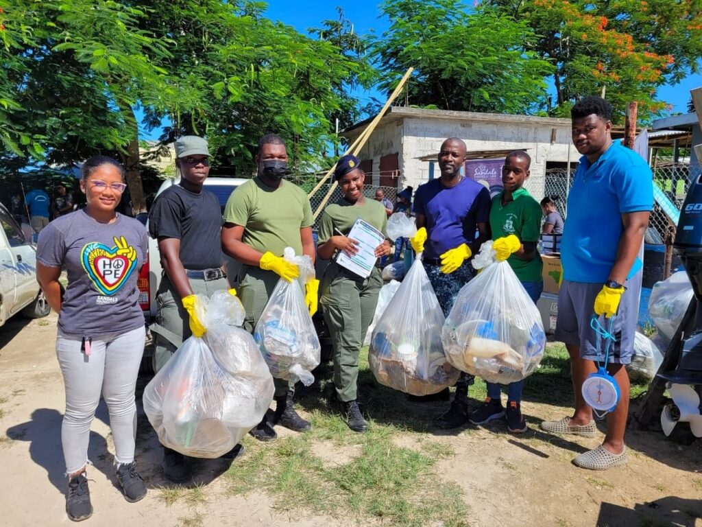 Black River High School Cadets (2nd left) Orlando Mahabeer, Javane Clarke, Rodalia Samuels and Shaquiel Bailey bring in bags of garbage to be weighed by Whitehouse Marine Sanctuary Manager, Diego Salmon (right). Working along with the students and sharing in this photo are Sandals Foundation Volunteer, Chloe-Ann Davis (left) and Jamaica Defence Force Chief Petty Officer, Gary Hanson (3rd right).