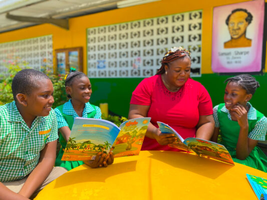 (From left) Jaheim Jerry, Dejanae Pearce and Mickera Fletcher engaging in a reading session with Grade 5 teacher at the Pell River Primary school Danielle Dixon in their recently renovated peace garden.