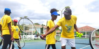 Tennis Pro, Norman Hall shows Khamiela Atlan how to correctly manoeuvre the racquet.