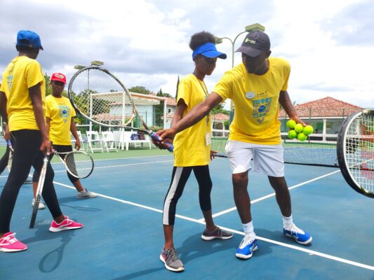  Tennis Pro, Norman Hall shows Khamiela Atlan how to correctly manoeuvre the racquet.