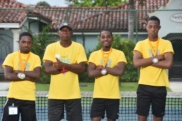  Tennis Pro, Norman Hal (2nd left) pauses for a power shot with three participants in the Sandals South Coast Youth Tennis Clinic (l-r); Romaine Samuels, Rojay Maylor and Joshua Wynter as they show off their medals received on day three of the Clinic. 