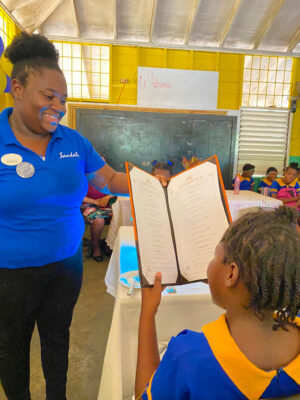 Restaurant Supervisor at Sandals Negril Keithia Duncan, walks this Negril Primary School student through the ordering process and the different courses that make up a four course meal