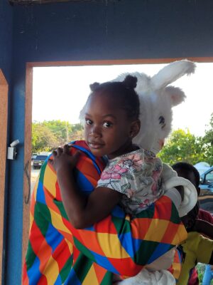 Four-year-old Antonique Saunders of the Whitehouse community affectionately shares a hug with the Sandals’ Easter bunny at her first Easter treat.